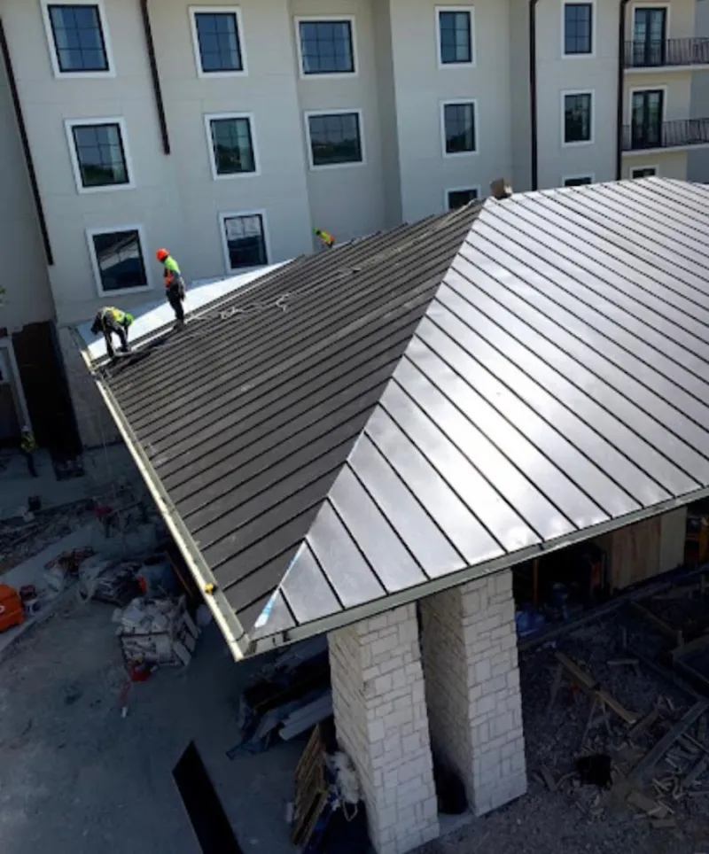 Crew installing standing seam metal roof panels on a commercial project in Middleborough